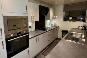 2 Bedroom Apartment - Sleeps 4 Free Parking Wifi في Pollokshaws: مطبخ مع حوض وموقد الفرن العلوي