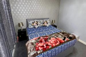2 Bedroom Apartment - Sleeps 4 Free Parking Wifi في Pollokshaws: غرفة نوم بها سرير عليه زهور