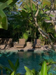 een zwembad met stoelen, bomen en water bij Udãra Hideaway Villa in Toyapakeh