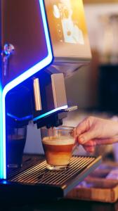 a person is making a cup of coffee on a espresso machine at Hotel Maxim in Arad
