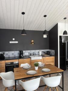 a kitchen with a wooden table and white chairs at Les pieds dans le sable in LʼÉpine +3 photos