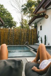 a person laying on a couch next to a swimming pool at Casa Sinabowewa in Ahangama