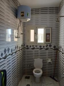 a bathroom with a white toilet and a window at Essa Apartment in Safaga  +6 photos