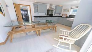 une cuisine avec une table en verre et une chaise dans l'établissement Shippenrill Croyde - Sleeps 14 - Hot Tub option - Stylish Home with fire pit, table tennis & dog friendly, à Croyde
