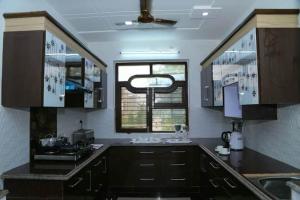 una cocina con armarios negros y una ventana en Kiran Home Stay, en Agra