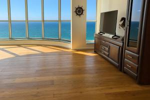 a living room with a television and large windows at Luxurious Beach apartments in Haifa