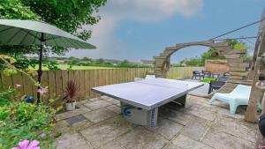 a patio with a table and an umbrella at Bag-End House - Unique home with Balcony, Beautiful Views, Ping Pong and Hot Tub option - Sleeps 14 in Croyde