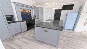 a kitchen with white cabinets and a counter top at Bag-End House - Unique home with Balcony, Beautiful Views, Ping Pong and Hot Tub option - Sleeps 14 in Croyde +24 photos