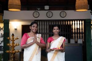 twee vrouwen die naast elkaar staan met een bord eten bij Vedic Village Retreat Kodungallur in Cochin +157 foto's