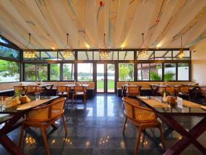 een restaurant met tafels, stoelen en ramen bij Vedic Village Retreat Kodungallur in Cochin