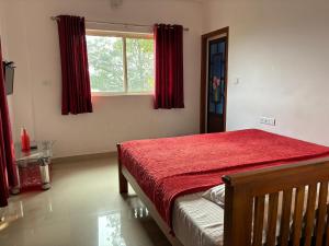 une chambre avec un lit rouge et une fenêtre dans l'établissement Tea Haze Cottage, à Anachal