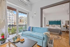 ein Wohnzimmer mit einer blauen Couch und einem Bett in der Unterkunft h2h Kalypso #Luxury, in 5' Port, in 1'metro, Airport, Athens smART, hi-tec in Piräus