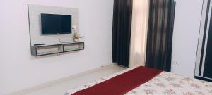 Un dormitorio con una cama y un televisor en la pared. en Kiran Home Stay, en Agra