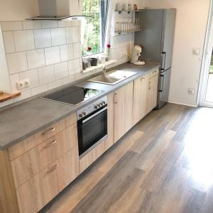 een keuken met houten kasten en een roestvrijstalen koelkast bij Ferienchalet Flößwehrtal in Bad Lauterberg +2 foto's