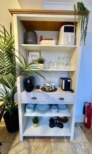 a white shelf with dishes and plants in a room at 1Bd Apt City Centre Contractor Friendly in Wolverhampton