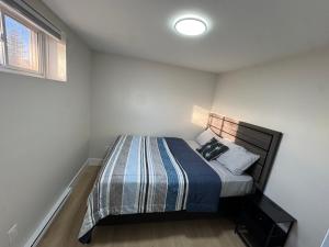 ein kleines Schlafzimmer mit einem Bett mit gestreifter Decke in der Unterkunft Cozy & Stylish Retreat with Modern Comforts in Moncton
