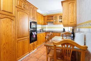 une cuisine avec des armoires en bois et une table et des chaises dans l'établissement Apartamento Terraza Los Realejos, à Los Realejos