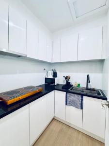 Cozy Retreat close to Monash Uni and Chadstone SS في Oakleigh South: مطبخ ابيض مع دواليب بيضاء وموقد