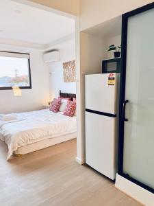 MetaWise Cozy Retreat close to Monash Uni and Chadstone U3 في Oakleigh South: غرفة نوم بسرير وثلاجة بيضاء