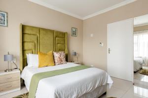 a bedroom with a large bed with a green headboard at Gosheni Villas in White River