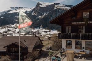 a flag in front of a building with a snow covered mountain at Chalet Brauerei in Lenk