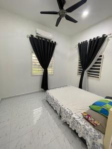 a bedroom with a bed and a ceiling fan at Qaseh homestay in Kota Bharu