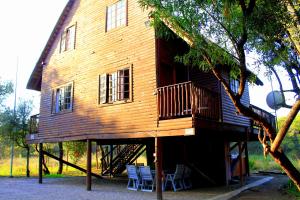 Casa de madera grande con terraza y sillas en River Ridge Log Home - Inside Dinokeng Big 5, en Klipdrift
