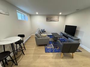 un soggiorno con un divano, una TV e un tavolo di Cozy & Stylish Retreat with Modern Comforts a Moncton
