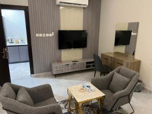 a living room with two chairs and a flat screen tv at تلال الفخامة in Hail