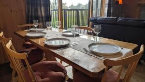 a wooden table with plates and wine glasses on it at Bracken Lodge in Dalavich +13 photos