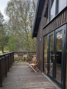 a wooden deck with chairs on the side of a building at Bracken Lodge in Dalavich