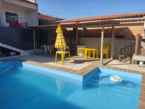 a swimming pool with a table and a yellow umbrella at Casa Refúgio in Ibicoara