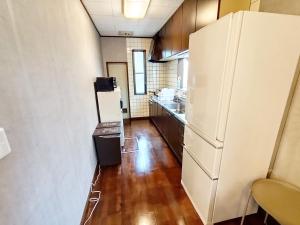 a small kitchen with a refrigerator and a wooden floor at 12名迄OK 5LDK ビーチまで徒歩3分 BBQ完備 駐車場5台White sun villa in Shirako