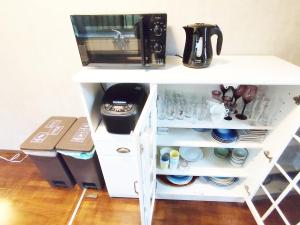 a white cabinet with dishes and a microwave at 12名迄OK 5LDK ビーチまで徒歩3分 BBQ完備 駐車場5台White sun villa in Shirako +9 photos