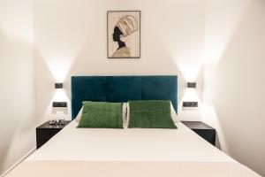 una camera da letto con un grande letto bianco con cuscini verdi di Cielo y Mar a Valencia