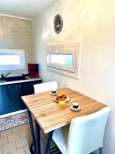 a kitchen with a wooden table and white chairs at Le Chant des Oiseaux-Campagne-SPA-Parking in Abbeville +14 photos