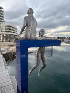 Una estatua de una mujer y un hombre sentados en el agua. en Family comfort across the road from North Beach, en Shellharbour