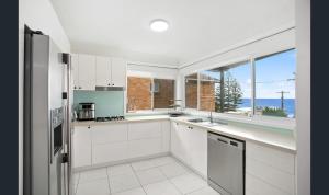 Una cocina con gabinetes blancos y una ventana grande. en Family comfort across the road from North Beach, en Shellharbour
