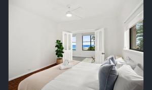 Un dormitorio blanco con una cama grande y una ventana. en Family comfort across the road from North Beach, en Shellharbour