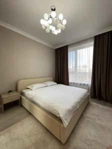 um quarto com uma cama grande e um lustre em GRAND-TURAN Bussiness em Astana
