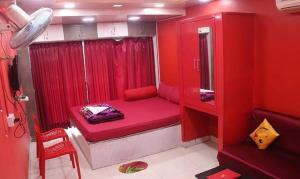 a red room with a small bed with a red curtain at FabHotel Rose in kolkata +14 photos