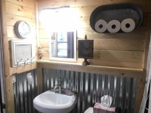 a bathroom with a sink and a clock on a wall at Amazing Conestoga Wagon for the Perfect Forest Getaway near Bryce Canyon, Utah in Alton