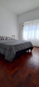 a bed in a room with a wooden floor at EMBE DEPARTAMENTO Necochea in Necochea