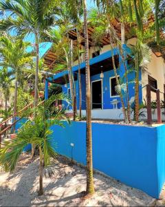 a blue house with palm trees in front of it at Pousada Solar de Maria e Hostel in Baixa de São Francisco
