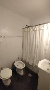 a bathroom with a toilet and a sink and a shower curtain at EMBE DEPARTAMENTO Necochea in Necochea +10 photos