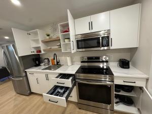 eine Küche mit Küchengeräten aus Edelstahl und weißen Schränken in der Unterkunft Cozy & Stylish Retreat with Modern Comforts in Moncton + 17 Fotos