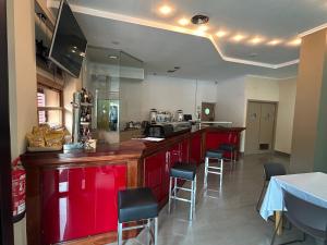 a restaurant with a red bar with stools at Hotel Eibar in Éibar