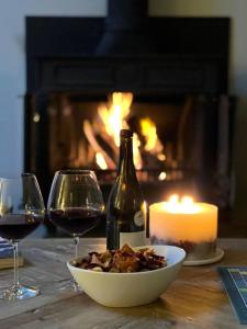 a table with a bottle of wine and a bowl of food and a candle at Brook Cottage in Kelling