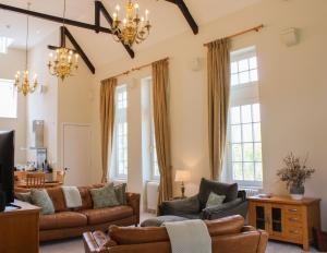 a living room with leather furniture and windows at The Dower House at Solsgirth Home Farm in Dollar