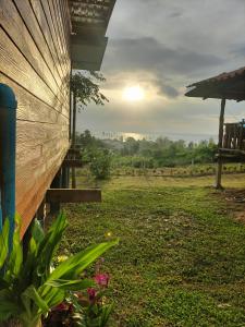 a house with the sun setting in a field at Baan Seaview Sunset in Phra Ae beach